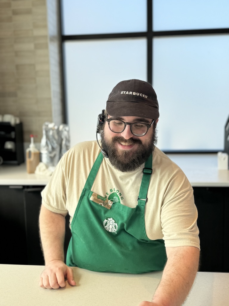 Kurt behind the bar in a green apron